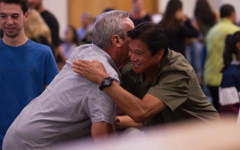 Two men embrace each other during a community engagement event. 